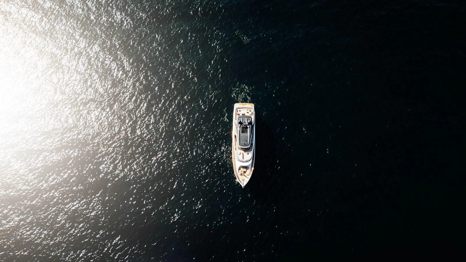 Aerial view of a yacht cruising on dark waters, showcasing its sleek design. aboard CHASE Yacht for Sale