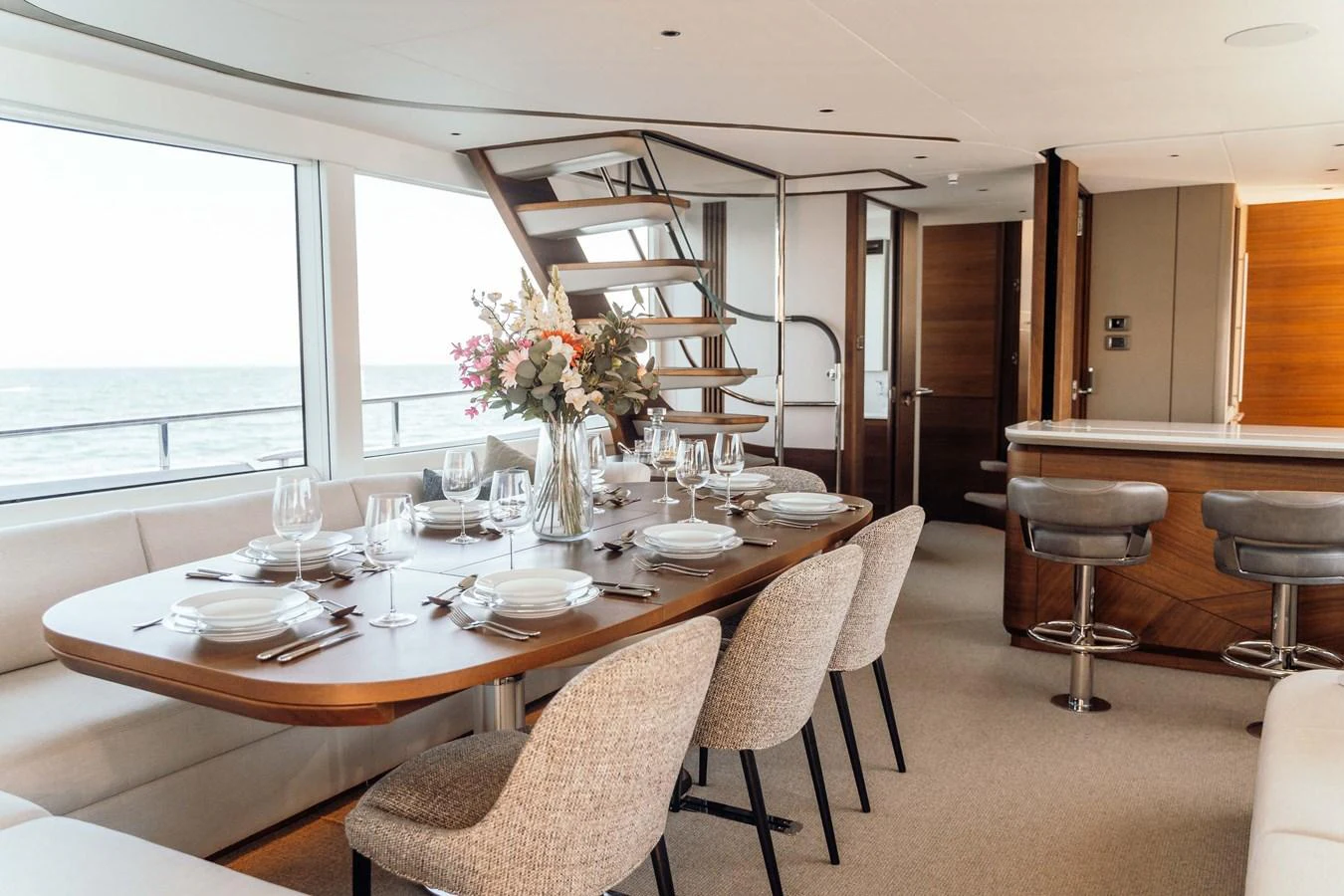 The yacht's dining area features a beautifully set table with a view of the sea through large windows. aboard CHASE Yacht for Sale