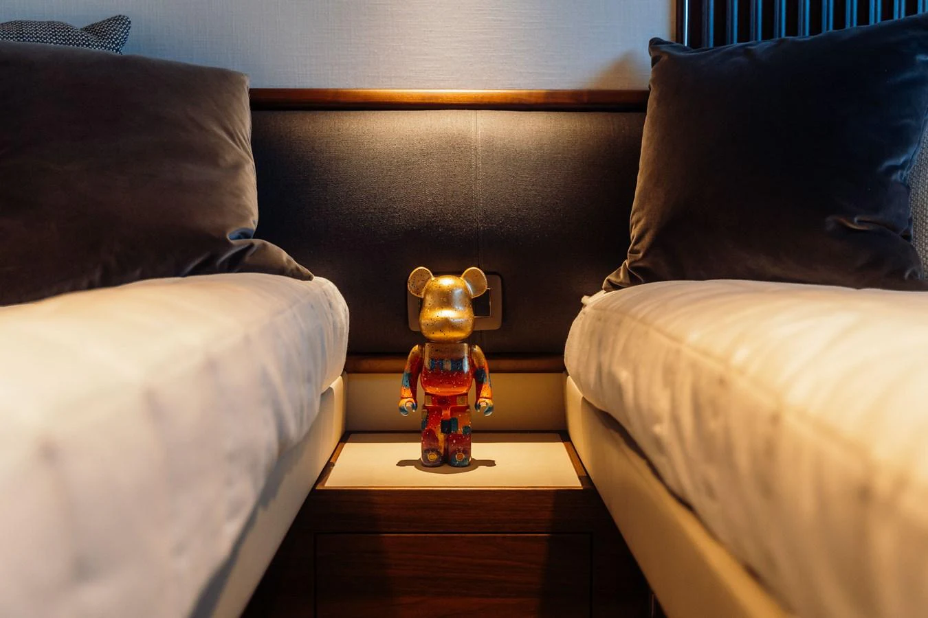A cozy twin cabin with a decorative bear figure placed between the beds. aboard CHASE Yacht for Sale