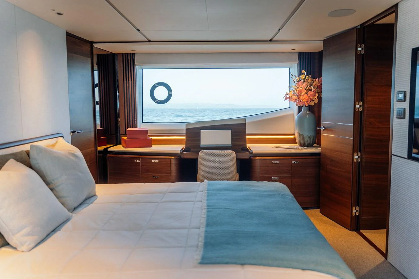 The stateroom features a large bed, elegant wood finishes, and a scenic ocean view through a wide window. aboard CHASE Yacht for Sale