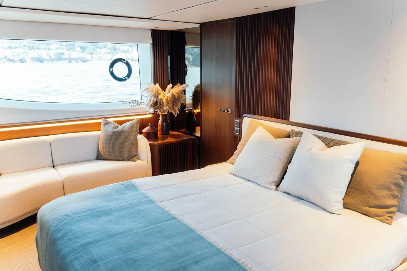 The stateroom features a luxurious bed with plush pillows and a cozy seating area by the window. aboard CHASE Yacht for Sale