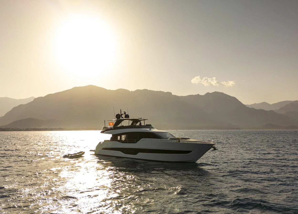 A sleek yacht glides on calm waters against a stunning sunset backdrop. aboard ORCA I Yacht for Sale