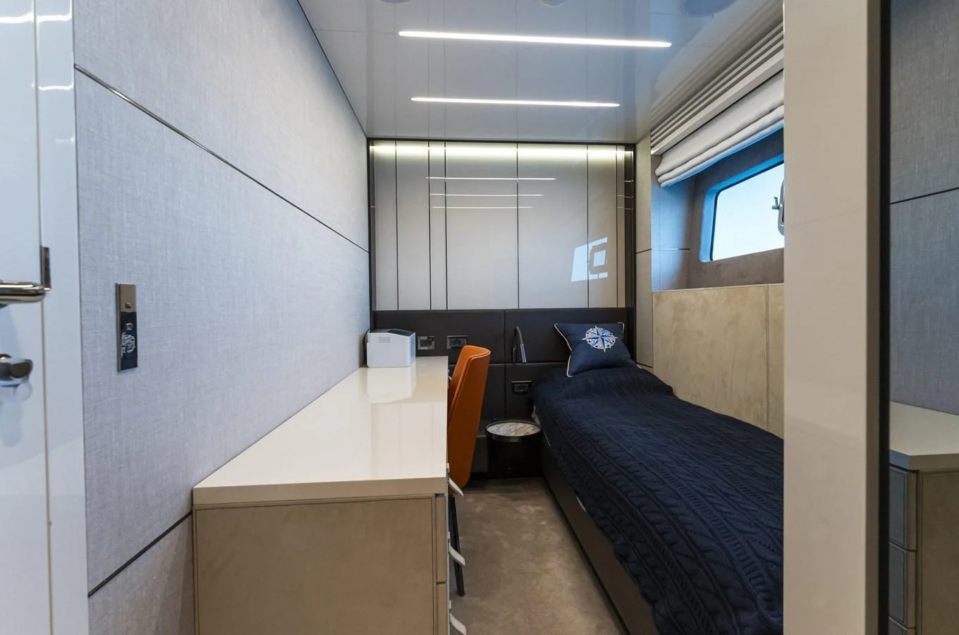 A modern guest cabin featuring a sleek design with a single bed and a work desk. aboard ORCA I Yacht for Sale