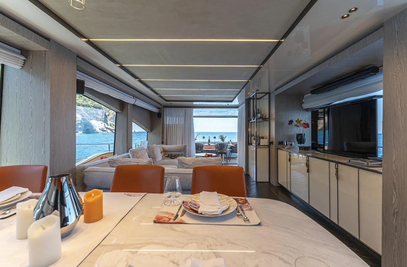 The yacht's salon features a luxurious dining area with a view of the sea through large windows. aboard ORCA I Yacht for Sale
