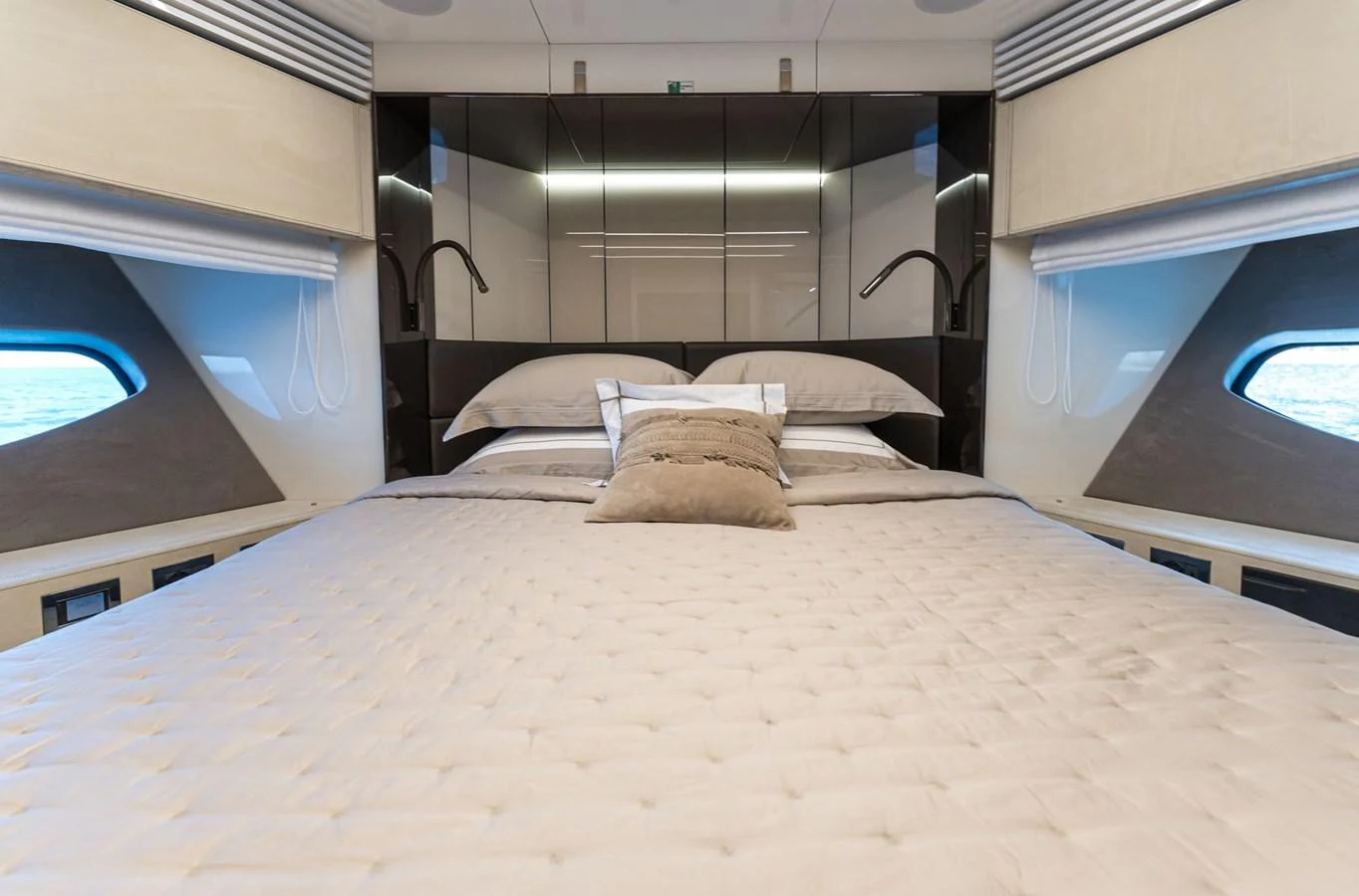 The master stateroom features a luxurious bed with elegant bedding and ample natural light from side windows. aboard ORCA I Yacht for Sale