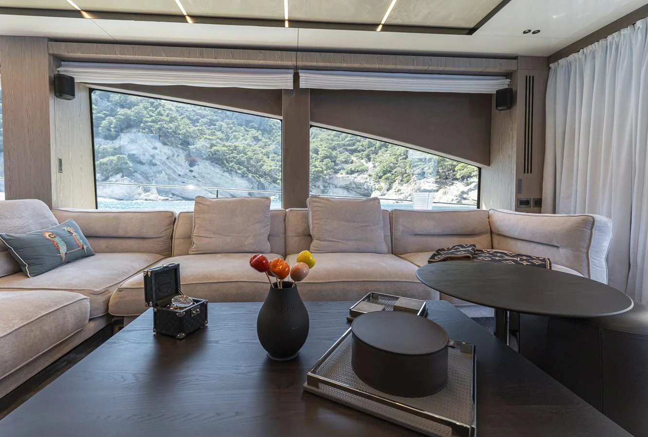 The yacht's interior features a spacious and elegant lounge area with large windows offering scenic views. aboard ORCA I Yacht for Sale