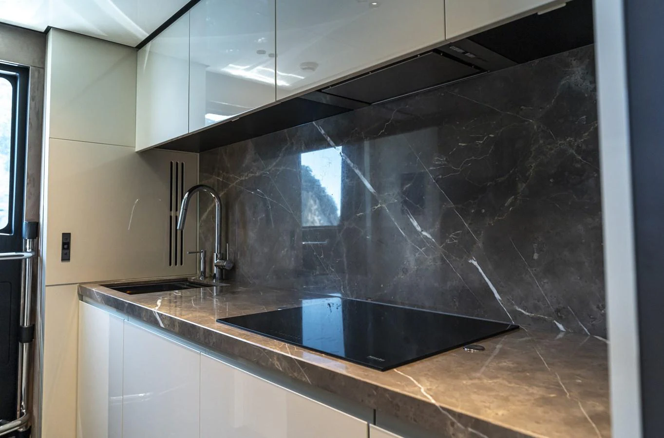 The yacht's galley features sleek cabinetry, a modern stovetop, and a stylish marble backsplash. aboard ORCA I Yacht for Sale