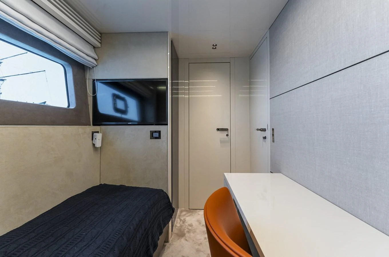 A modern and cozy cabin with a single bed, desk, and wall-mounted TV. aboard ORCA I Yacht for Sale