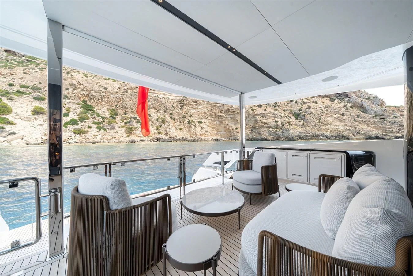 The aft deck offers a serene outdoor seating area with a stunning view of the surrounding cliffs and water. aboard 82 OCEAN ENCLOSED Yacht for Sale