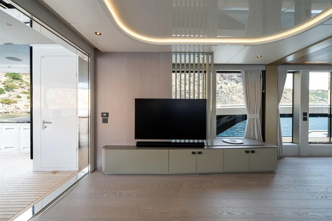 The yacht's interior features a modern entertainment area with a sleek TV setup and large windows offering scenic views. aboard 82 OCEAN ENCLOSED Yacht for Sale