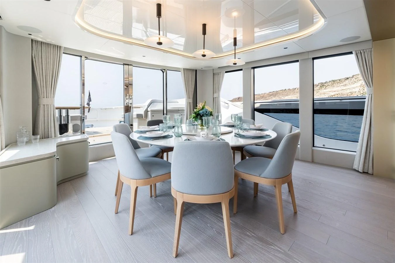 The yacht's dining area features a modern, elegant design with panoramic windows offering stunning sea views. aboard 82 OCEAN ENCLOSED Yacht for Sale