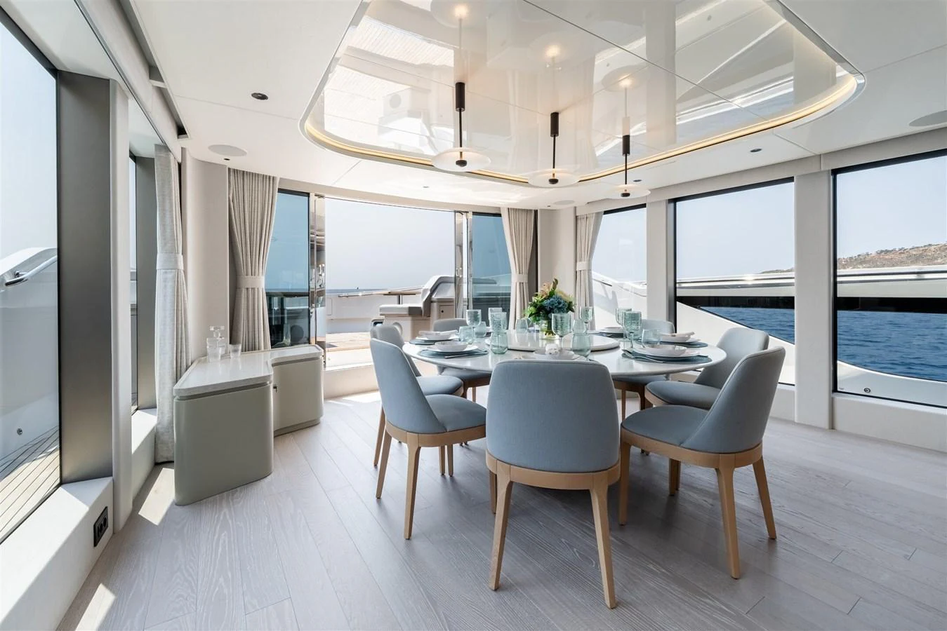 The yacht's dining area features a modern, elegant design with panoramic windows offering stunning sea views. aboard 82 OCEAN ENCLOSED Yacht for Sale