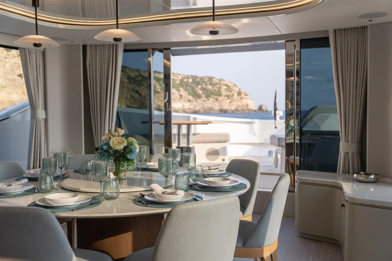 The elegant dining area offers a stunning view through large windows, seamlessly blending indoor and outdoor spaces. aboard 82 OCEAN ENCLOSED Yacht for Sale