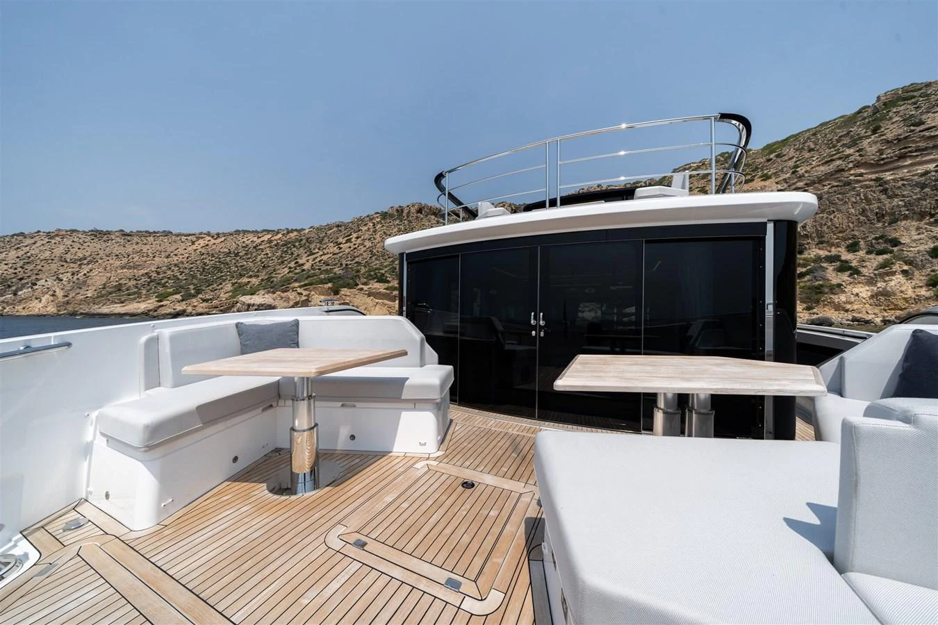The aft deck features elegant seating and dining areas with a scenic backdrop. aboard 82 OCEAN ENCLOSED Yacht for Sale
