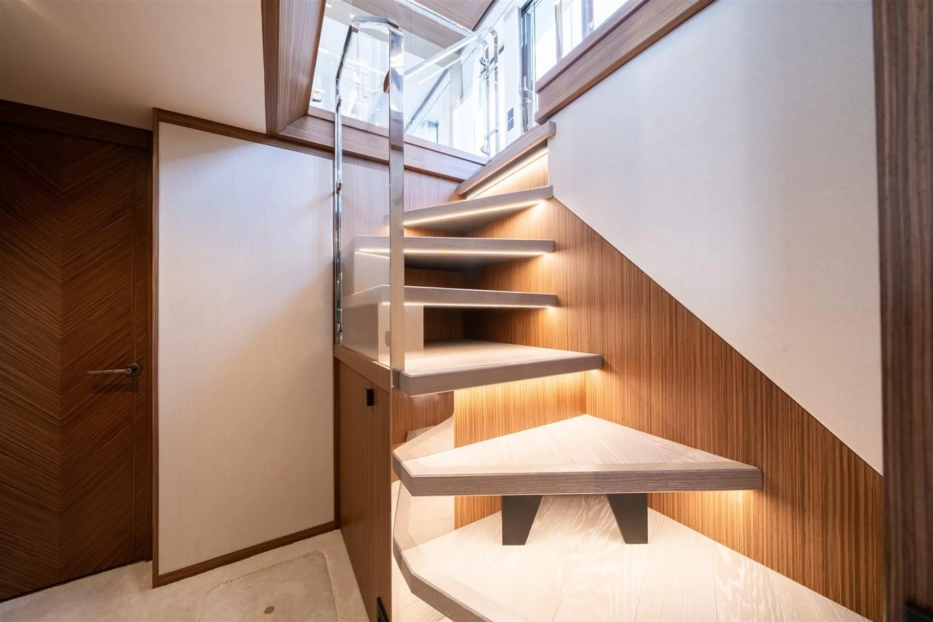 A modern, well-lit staircase with wooden accents and sleek design elements. aboard 82 OCEAN ENCLOSED Yacht for Sale