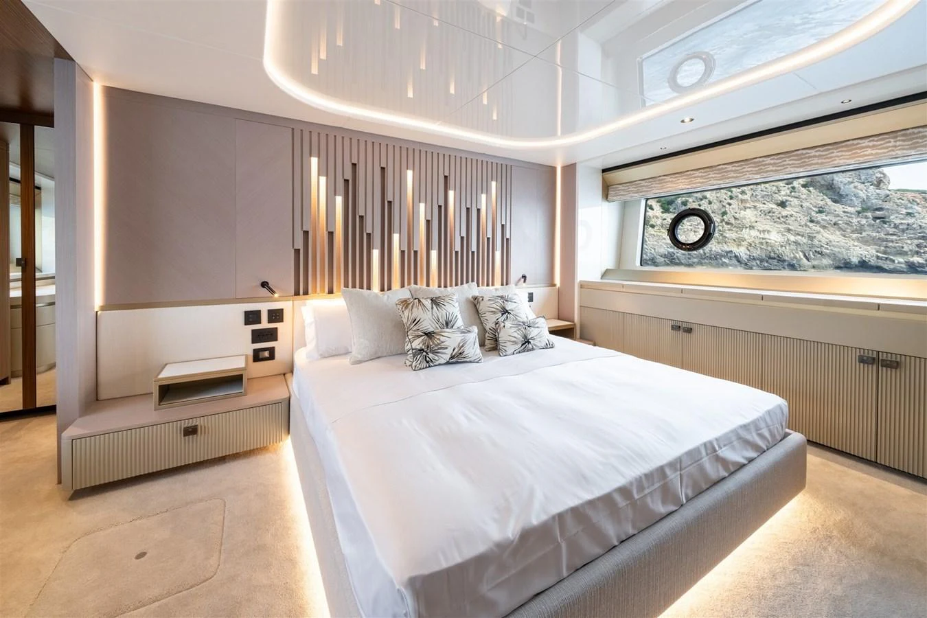 The master stateroom features a luxurious bed with elegant lighting and a large window offering scenic views. aboard 82 OCEAN ENCLOSED Yacht for Sale