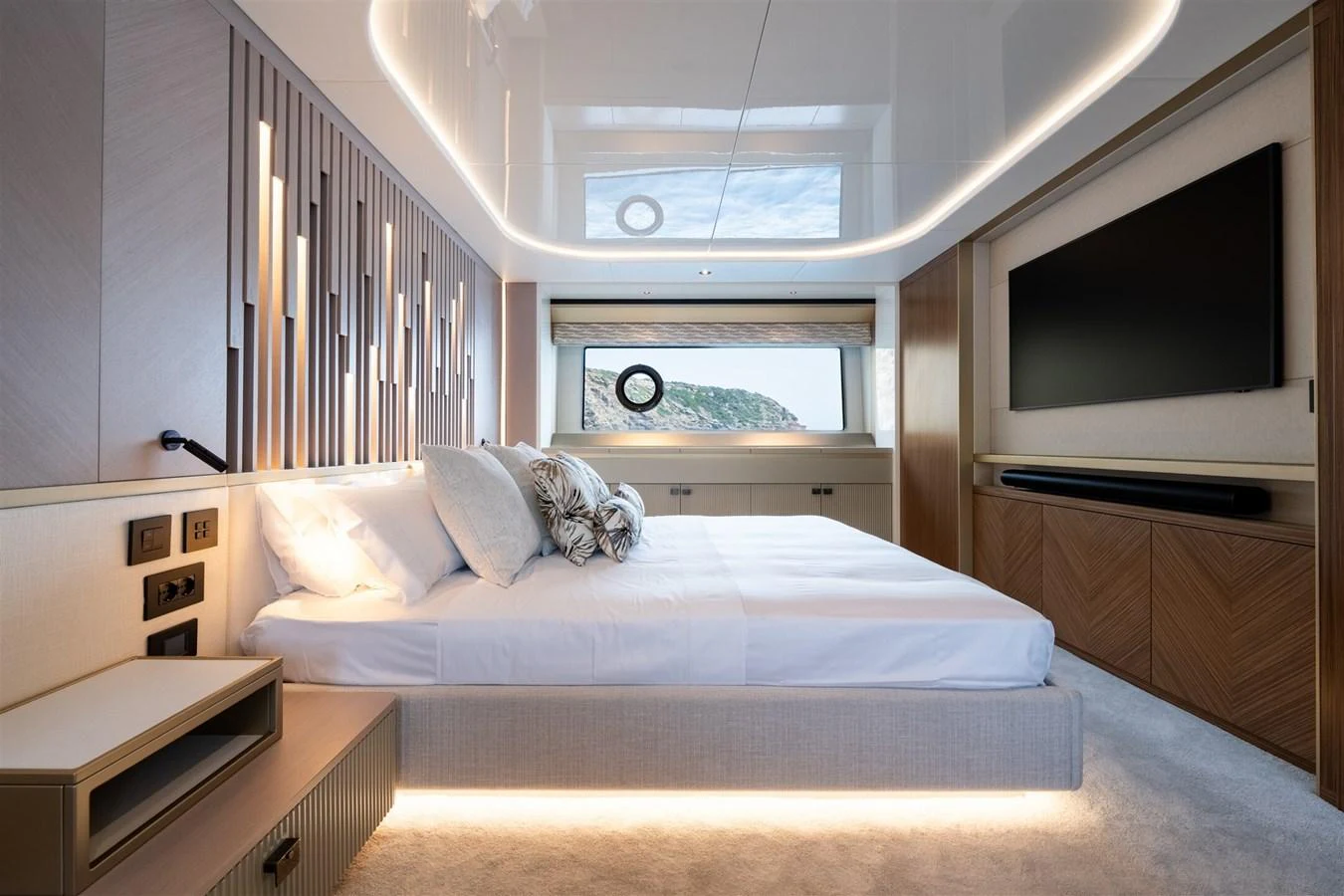 The stateroom features a luxurious bed with modern lighting and a large window offering scenic views. aboard 82 OCEAN ENCLOSED Yacht for Sale