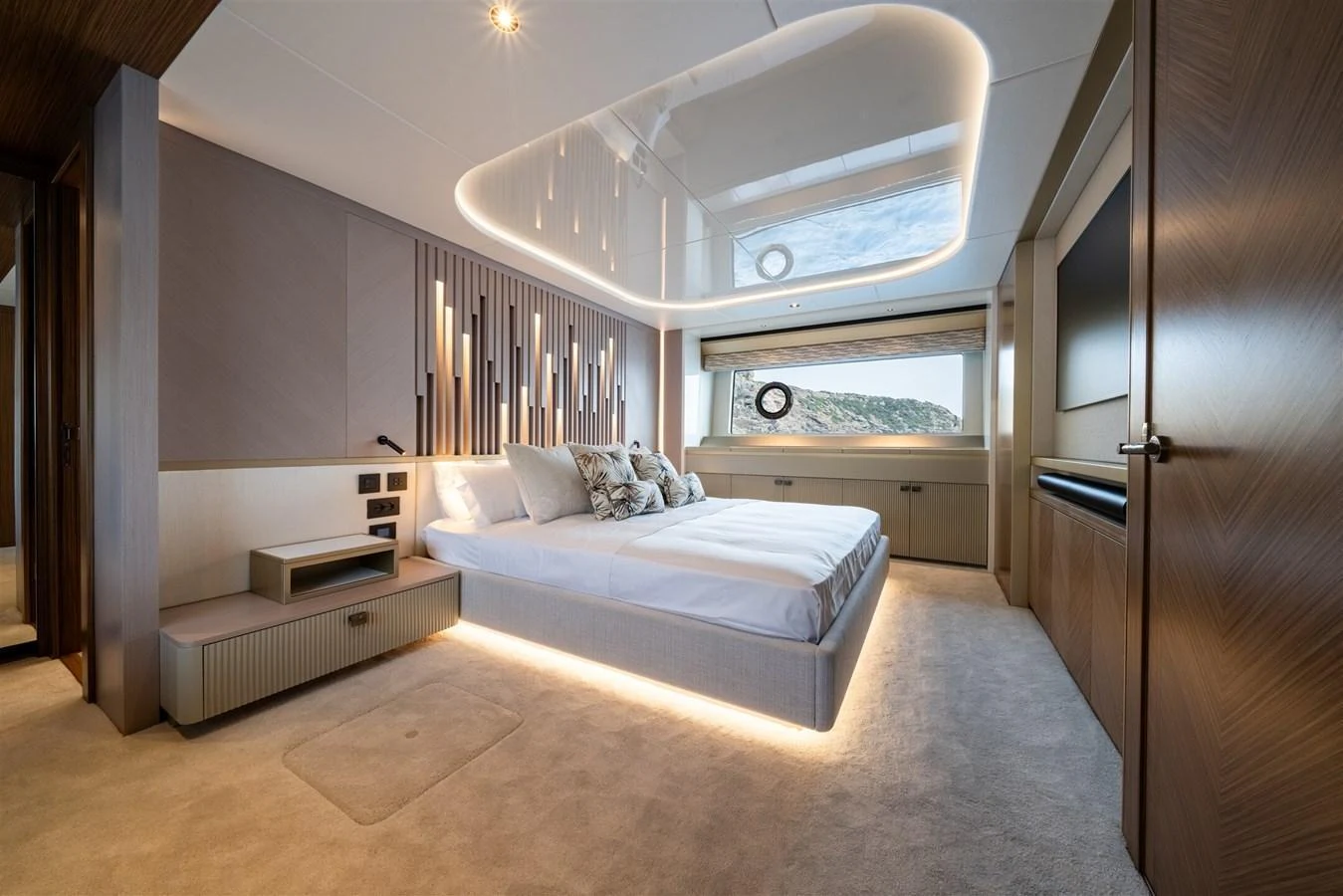 The master stateroom features a luxurious bed with elegant lighting and a scenic view through the window. aboard 82 OCEAN ENCLOSED Yacht for Sale