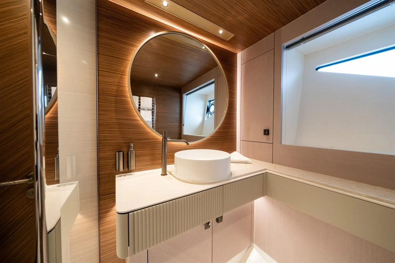 A luxurious yacht bathroom featuring a modern circular mirror and elegant fixtures. aboard 82 OCEAN ENCLOSED Yacht for Sale