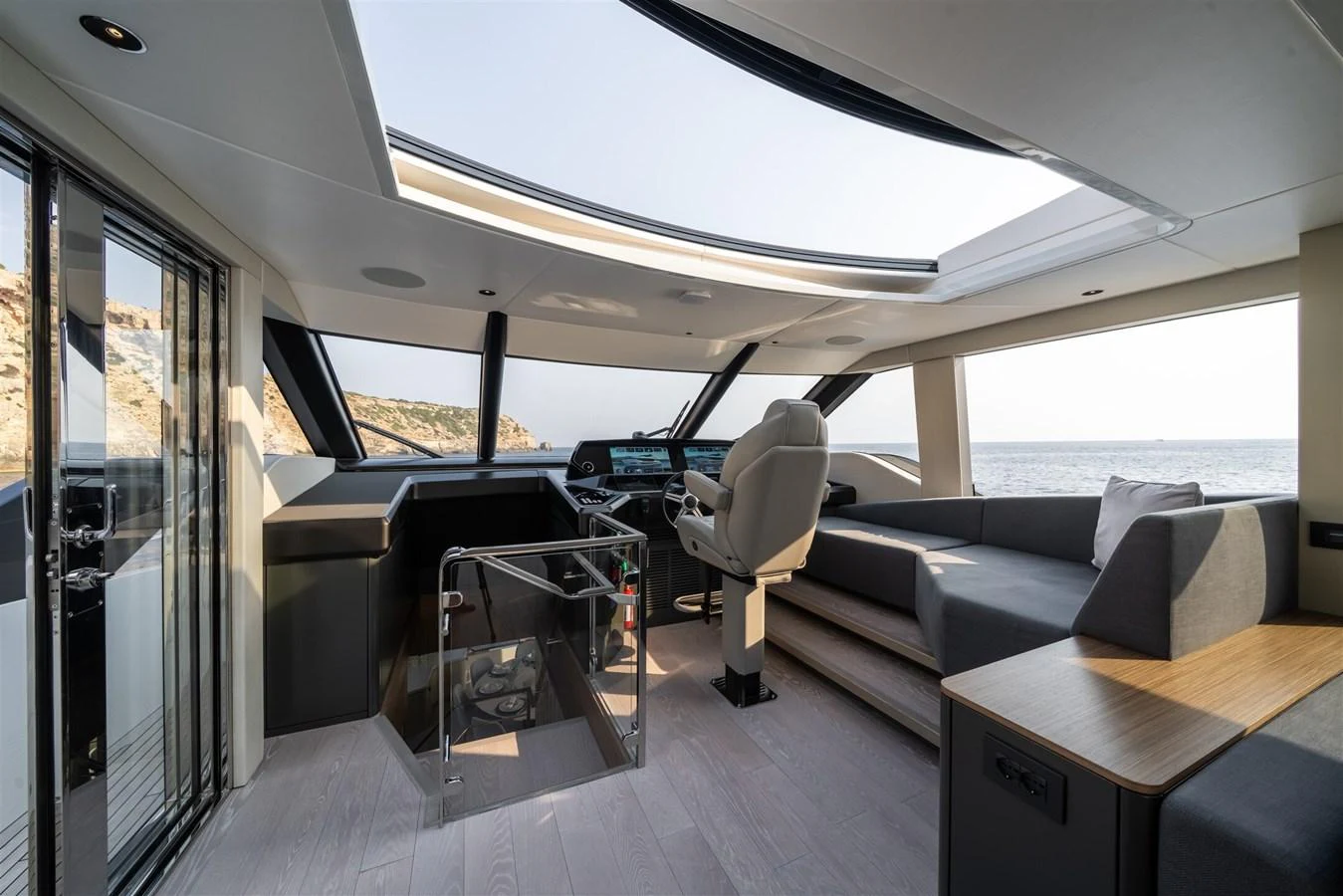 The helm area features a sleek design with panoramic windows offering stunning sea views. aboard 82 OCEAN ENCLOSED Yacht for Sale