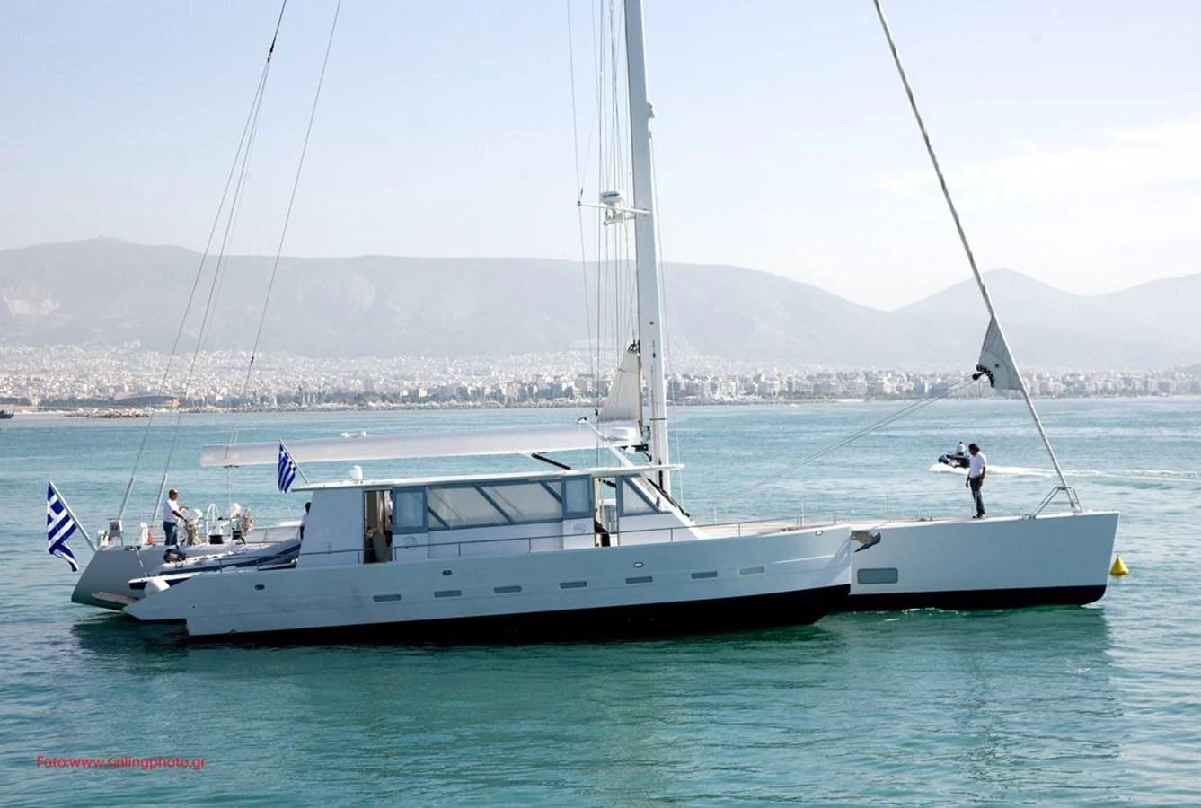A sleek, modern yacht glides gracefully on calm waters with a scenic coastal backdrop. aboard POLYTROPON II Yacht for Sale