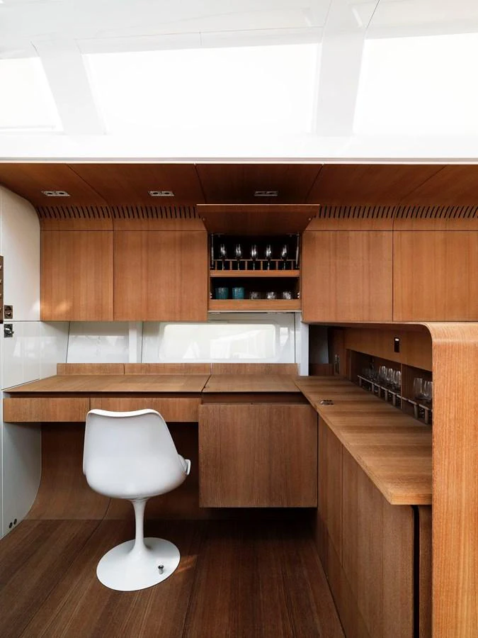 The yacht's galley features sleek wooden cabinetry and a modern white chair, creating a stylish and functional space. aboard POLYTROPON II Yacht for Sale