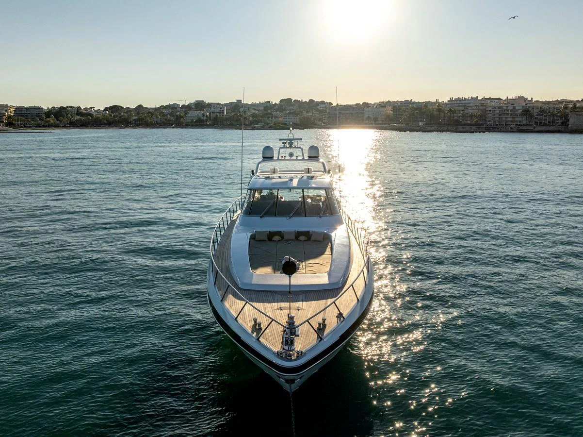 A sleek yacht glides on calm waters, illuminated by the setting sun. aboard K GRACE Yacht for Sale