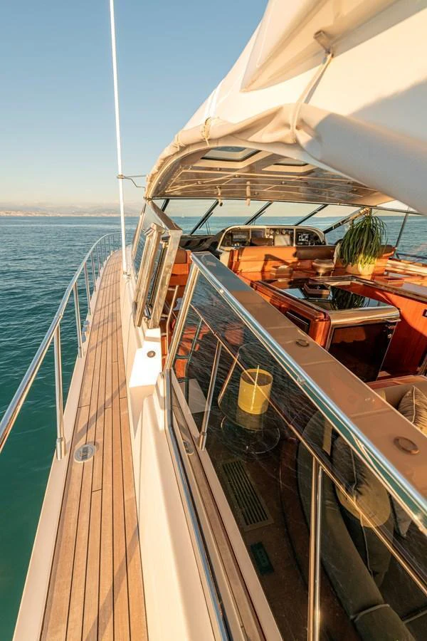 The yacht's side deck offers a seamless transition from the exterior to the interior, showcasing elegant wood finishes and ample seating. aboard K GRACE Yacht for Sale