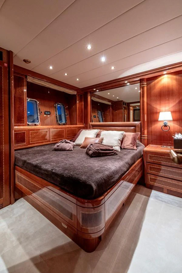 The stateroom features luxurious wood paneling and plush bedding, creating a warm and inviting atmosphere. aboard K GRACE Yacht for Sale