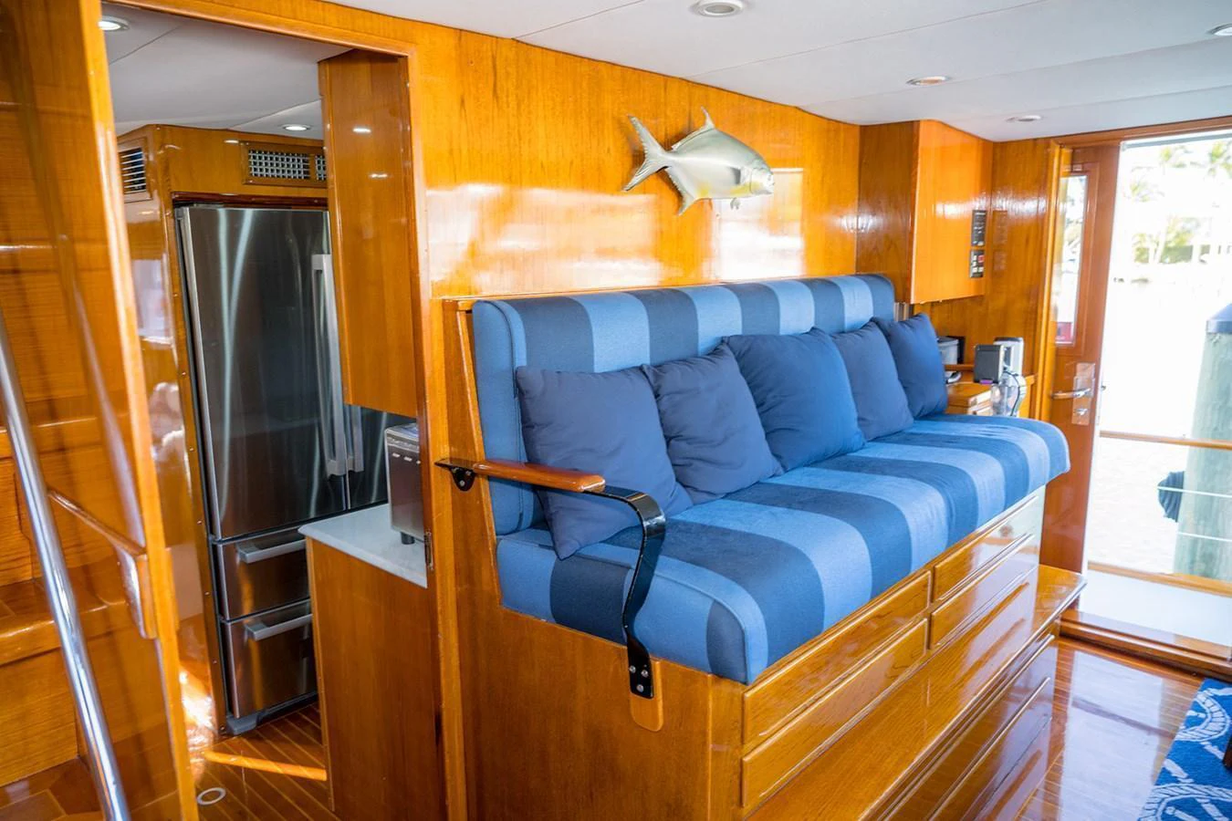 The yacht's interior features a cozy seating area with blue cushions and a polished wooden finish. aboard MAMA BEAR Yacht for Sale