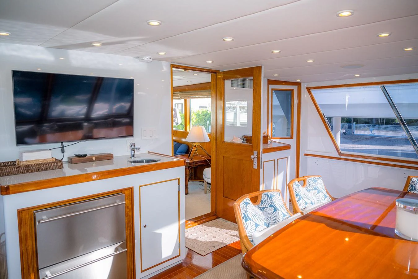 The yacht's interior dining area features a wooden table, comfortable seating, and a large TV. aboard MAMA BEAR Yacht for Sale
