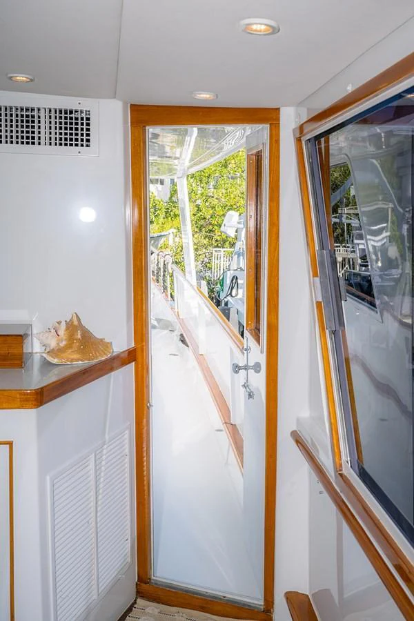 A cozy interior passageway with a view of the exterior deck through a glass door. aboard MAMA BEAR Yacht for Sale