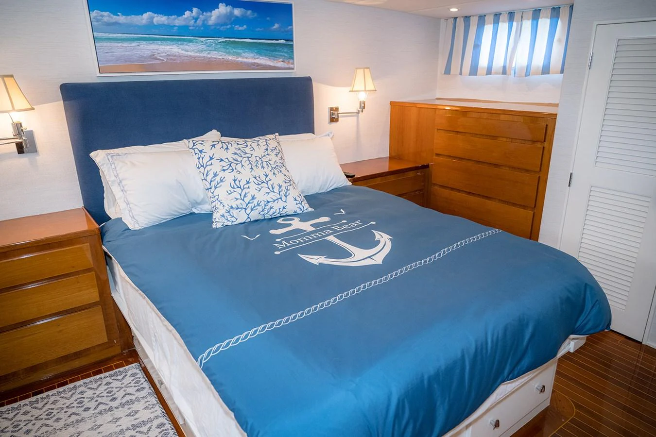 The cozy stateroom features a comfortable bed with nautical-themed bedding and warm wooden furnishings. aboard MAMA BEAR Yacht for Sale