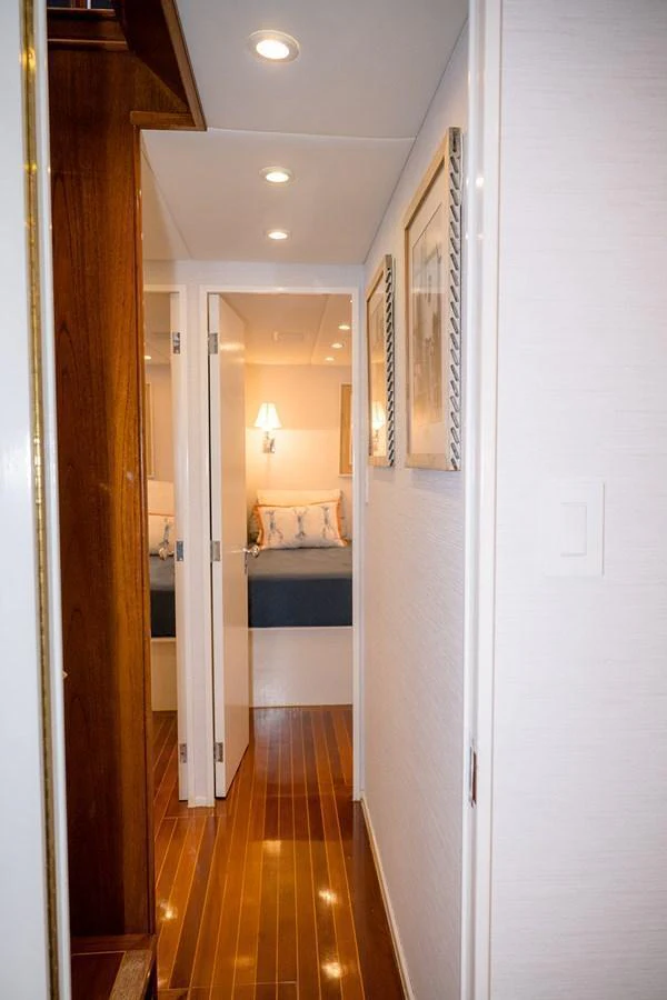 A well-lit hallway leads to a cozy stateroom with elegant decor. aboard MAMA BEAR Yacht for Sale