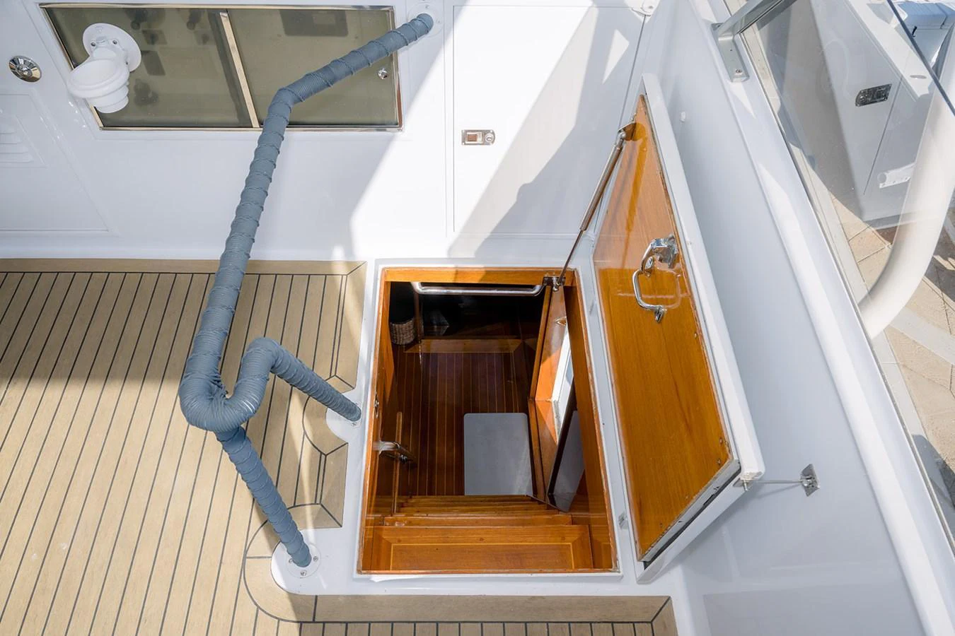 A view of a yacht's stairway leading below deck, showcasing wooden steps and a hatch. aboard MAMA BEAR Yacht for Sale