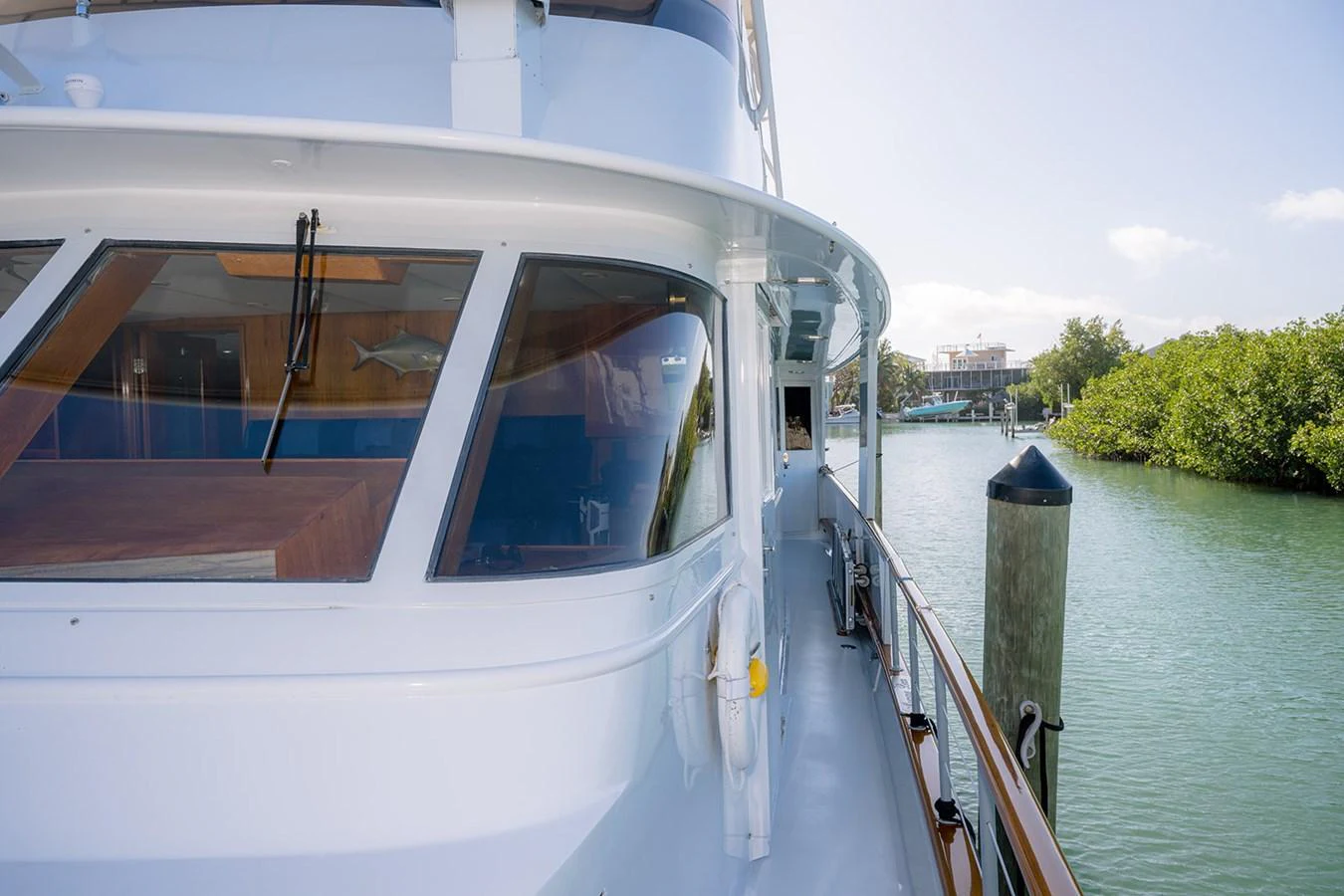 The yacht is docked, showcasing its sleek exterior and spacious side deck. aboard MAMA BEAR Yacht for Sale