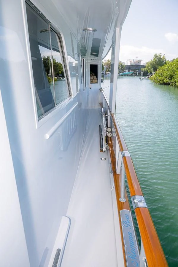 The side deck of the yacht offers a sleek and polished walkway with a view of the serene waters. aboard MAMA BEAR Yacht for Sale