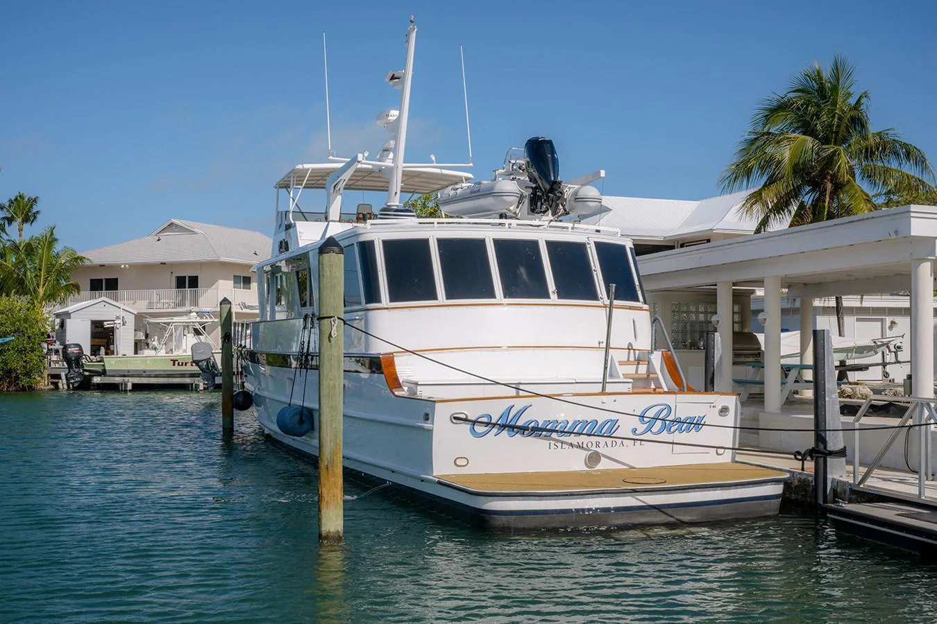 The yacht is docked at a marina, showcasing its sleek exterior design under a clear blue sky. aboard MAMA BEAR Yacht for Sale