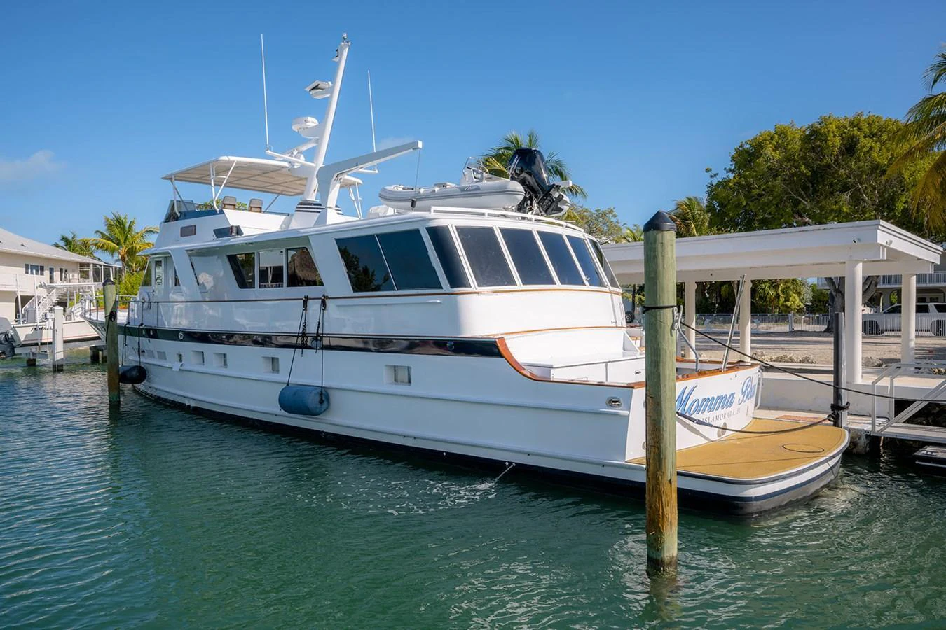 A sleek yacht is docked in a serene marina, showcasing its elegant design and spacious deck. aboard MAMA BEAR Yacht for Sale