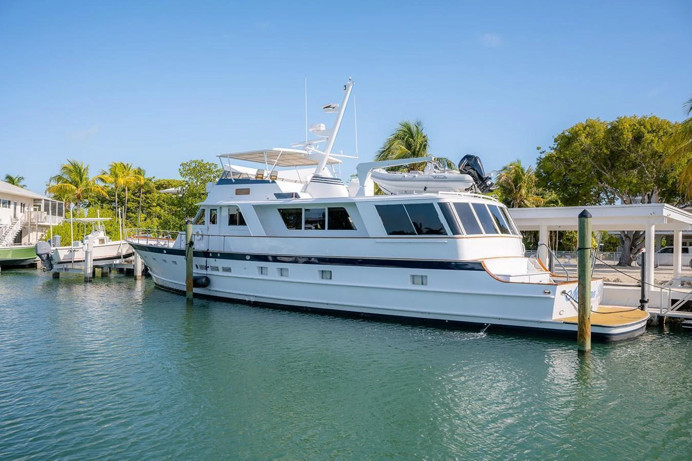 A classic motor yacht is docked in a serene marina under a clear blue sky. aboard MAMA BEAR Yacht for Sale