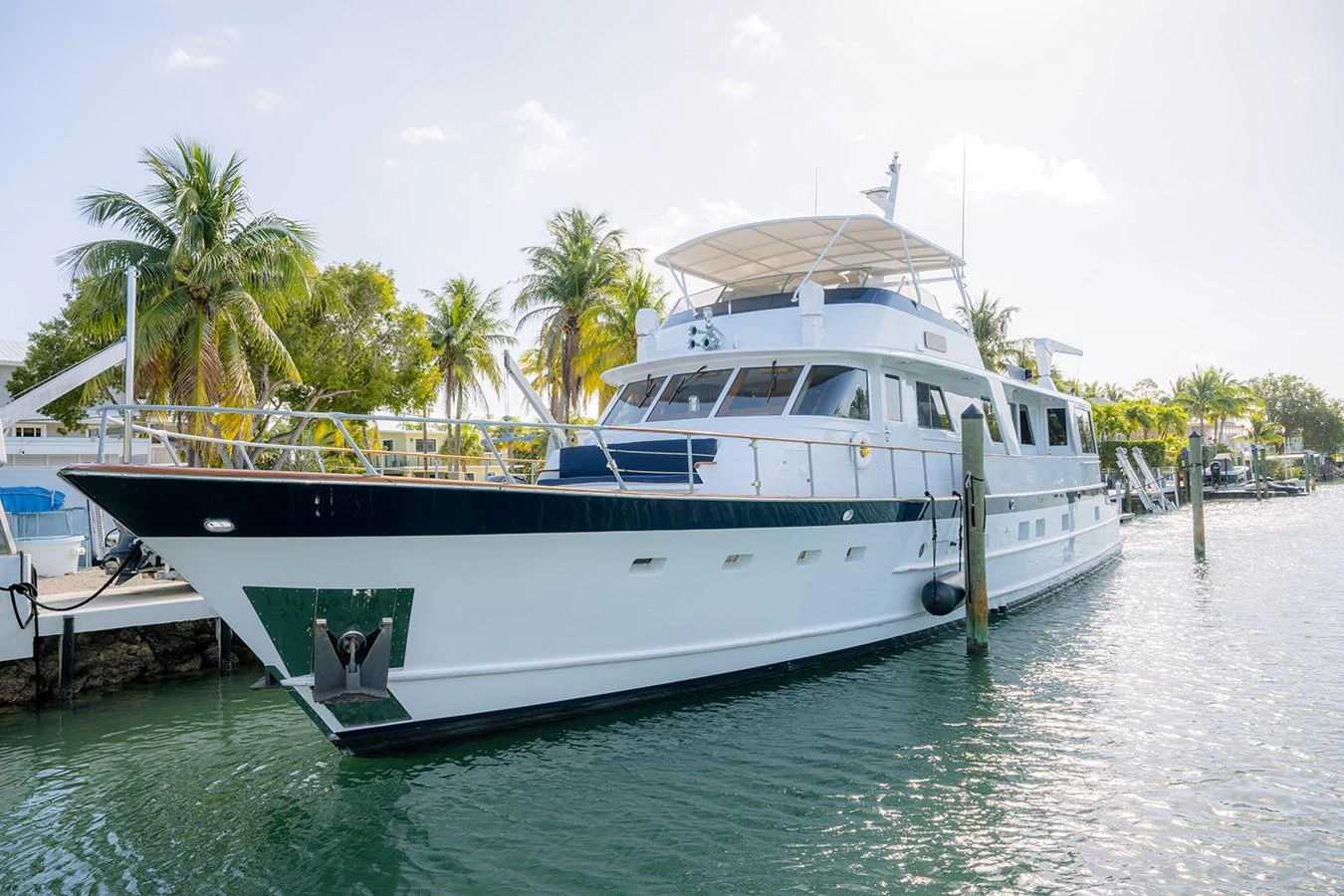 This elegant yacht is docked in a serene marina, showcasing its sleek design and inviting outdoor spaces. aboard MAMA BEAR Yacht for Sale