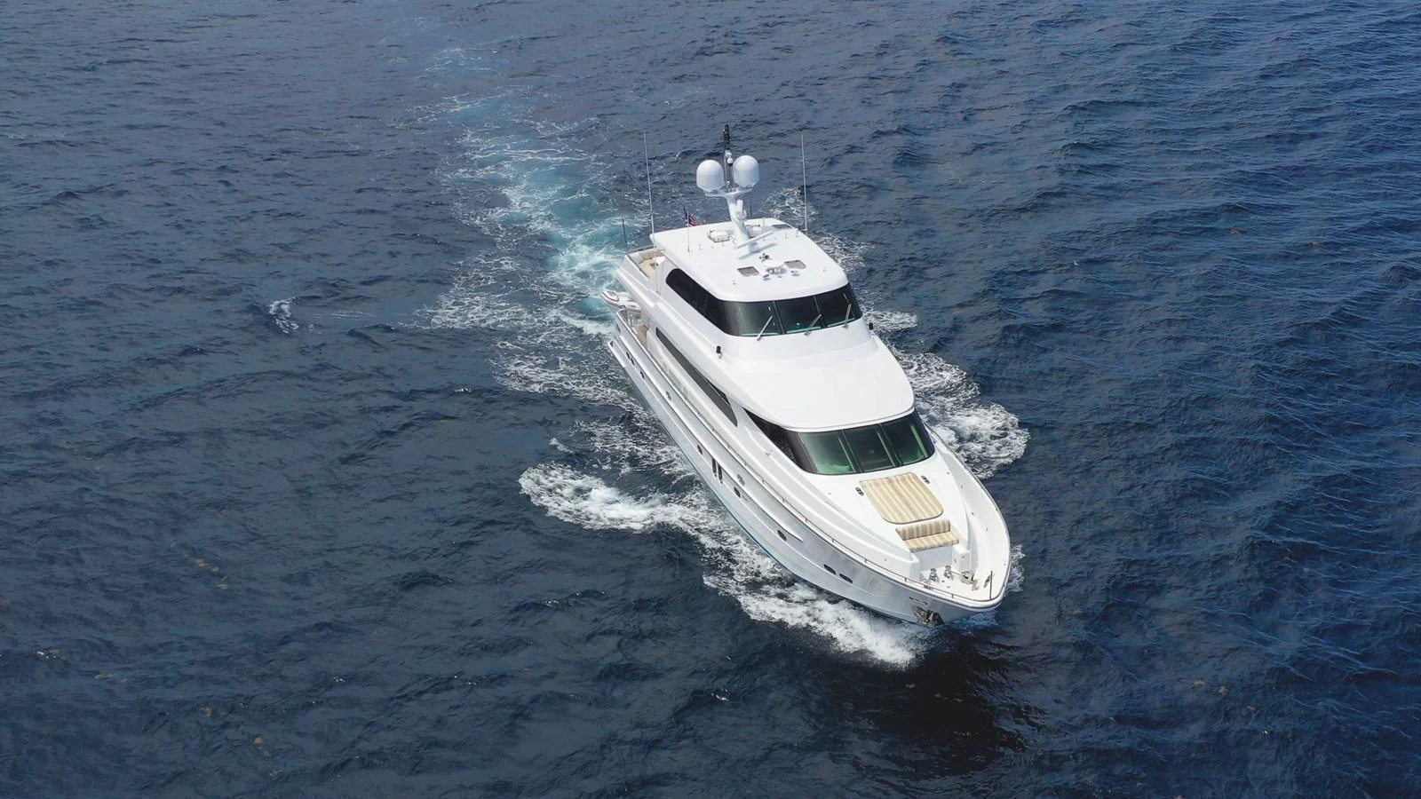 A sleek white yacht cruises smoothly through the open sea, leaving a gentle wake behind. aboard PRIME TIME Yacht for Sale