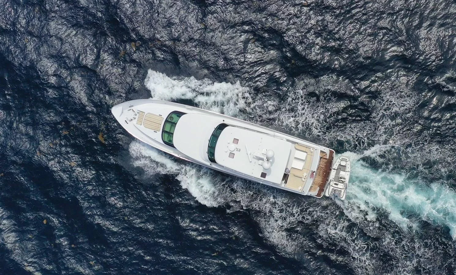 A sleek yacht cruises through the water, showcasing its elegant design from an aerial perspective. aboard PRIME TIME Yacht for Sale