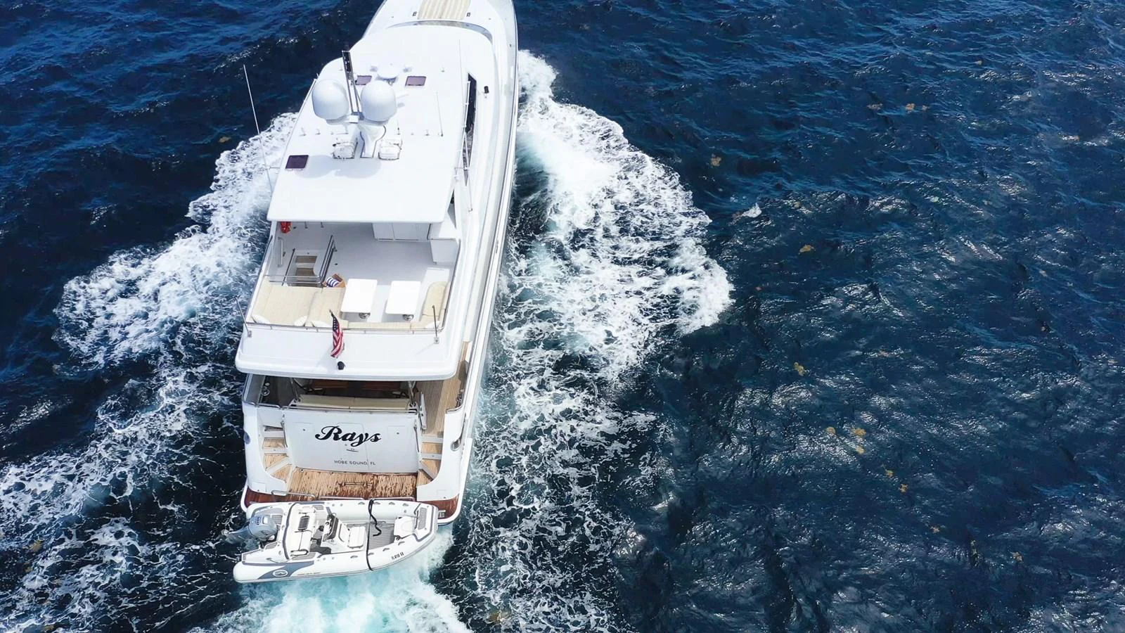 A luxurious yacht cruising through the open sea, leaving a trail of white foam in its wake. aboard PRIME TIME Yacht for Sale