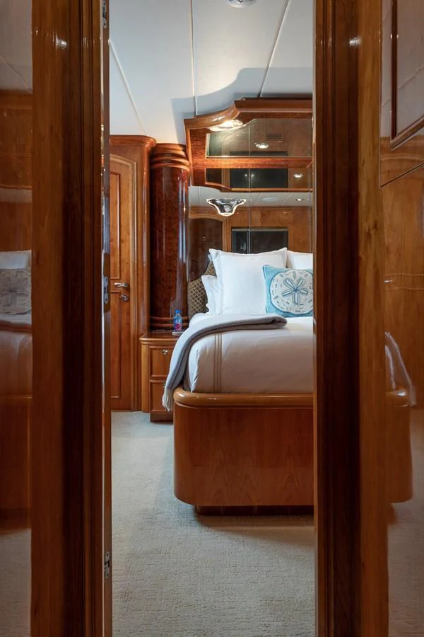 A luxurious stateroom featuring elegant wood finishes and plush bedding. aboard PRIME TIME Yacht for Sale