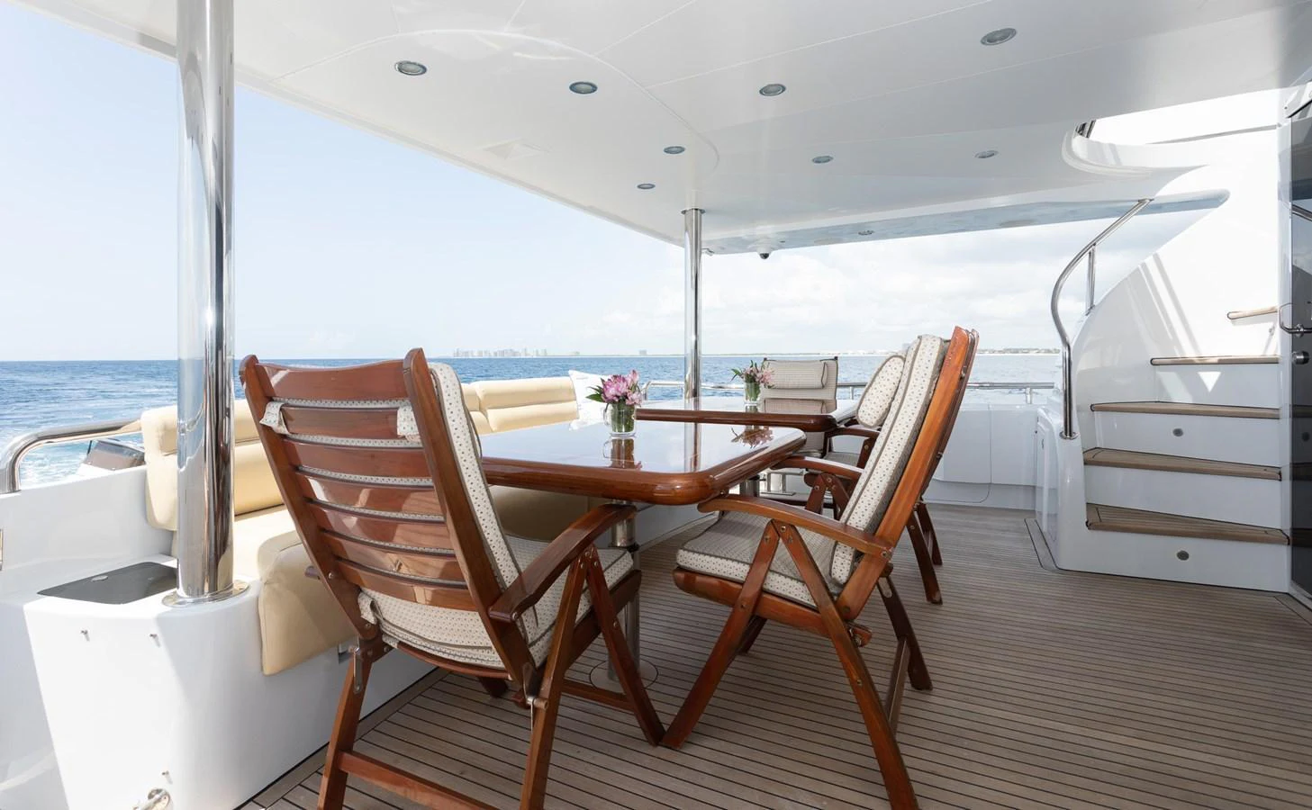 The aft deck features a spacious dining area with elegant wooden chairs and a polished table, perfect for alfresco meals with a view of the sea. aboard PRIME TIME Yacht for Sale