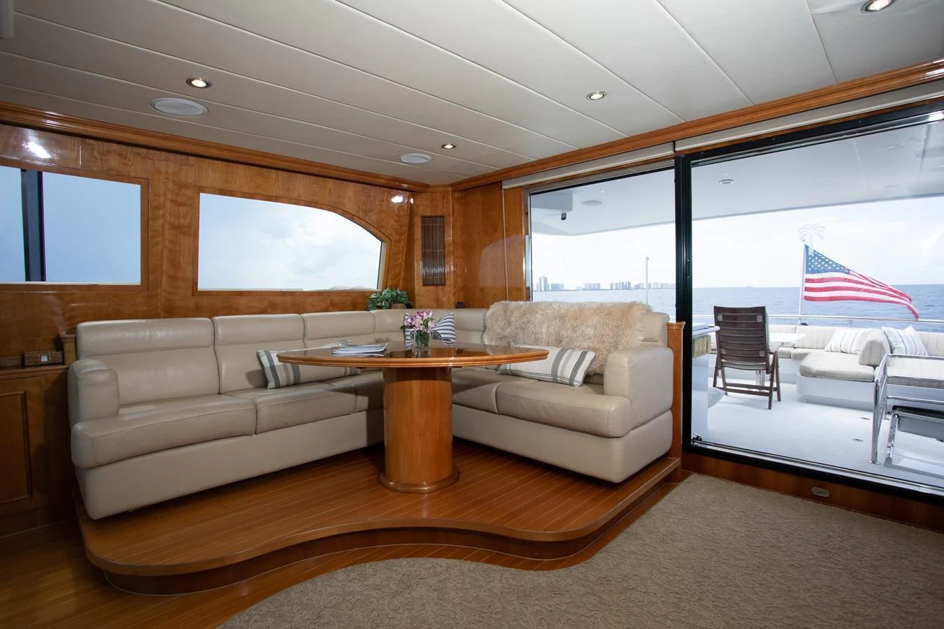 The salon features a comfortable seating area with a view of the aft deck and ocean beyond. aboard PRIME TIME Yacht for Sale