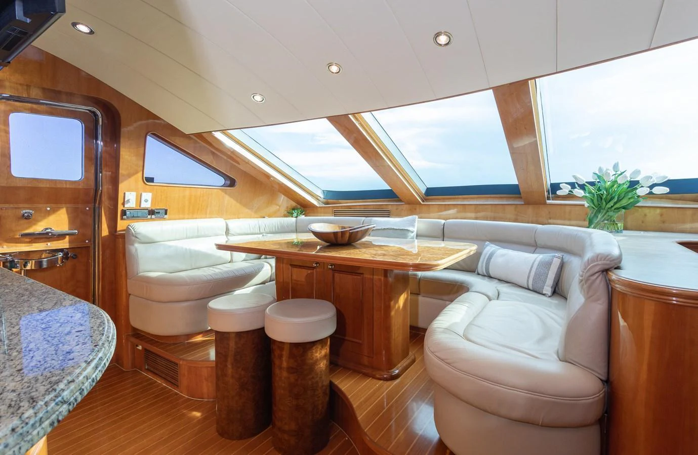 The saloon features plush seating, a wooden table, and large windows for natural light. aboard PRIME TIME Yacht for Sale