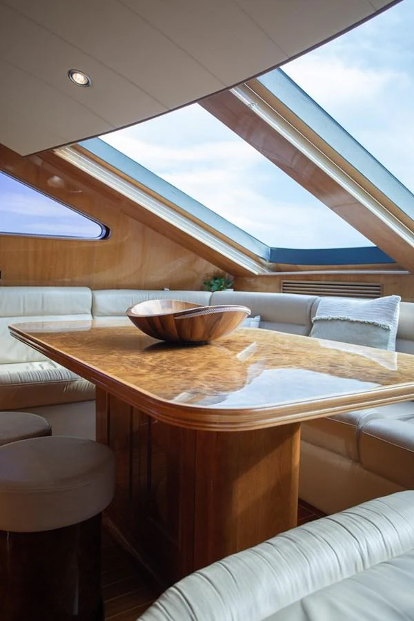 The salon features a luxurious seating area with a polished wooden table and ample natural light from large skylights. aboard PRIME TIME Yacht for Sale