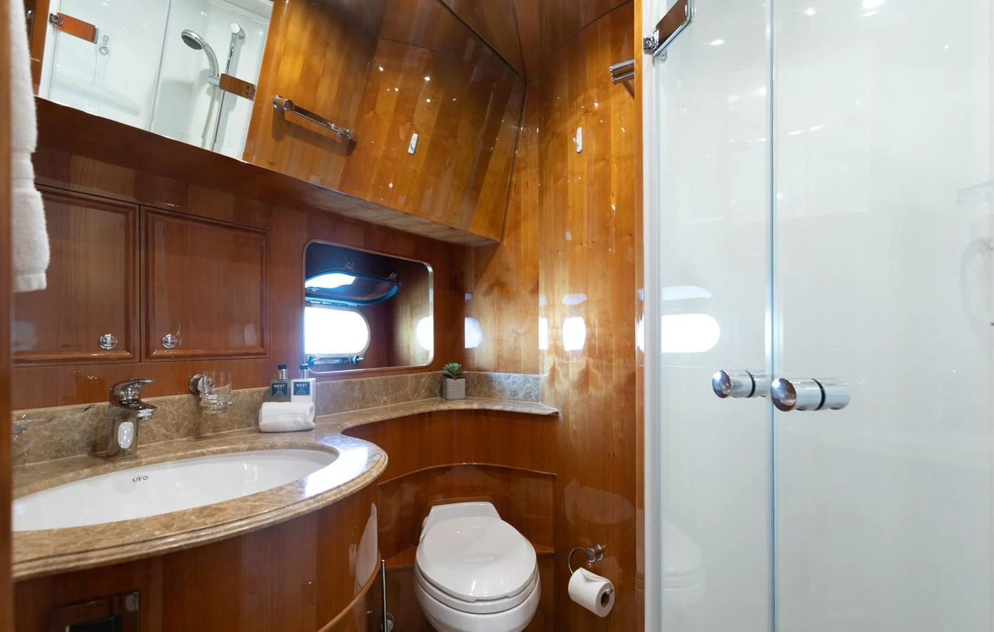 The yacht's bathroom features elegant wood paneling and a sleek glass shower enclosure. aboard PRIME TIME Yacht for Sale